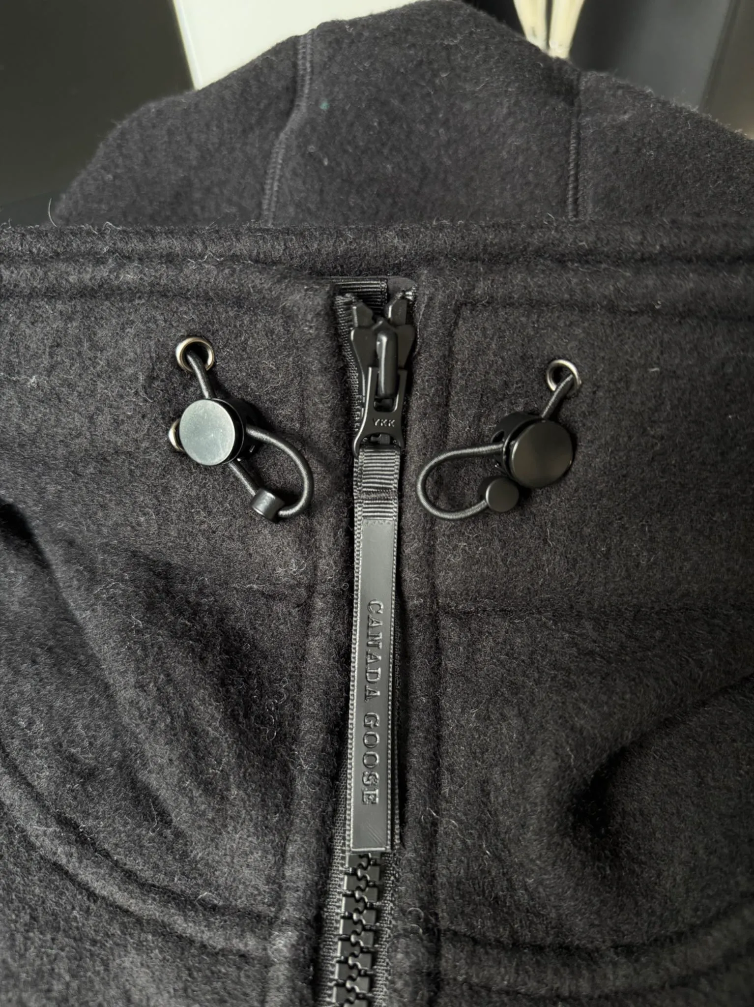 P660 Canada Goose Fleece Wool Badge Hooded Jacket Fabric selection: Wool fleece fabric blended with wool as the main body and a very small amount of spandex and polyester fiber. Wool is a core natural ingredient that provides unparalleled temperature regulation, antibacterial and anti-odor properties and a skin-friendly feel. The feeding of a small amount of spandex gives the fabric a certain degree of four-way elasticity, making it non-restrictive during daily activities. As the basis of fleece's structure, polyester fiber enhances the fabric's durability, wrinkle resistance and quick-drying properties. It contributes to the loft of the fleece and provides functions such as trapping air.  Detail 1: The sleeves and hem are closed with 2×2 ribbing. Its strong elasticity can closely fit wrists and waists of different thicknesses, forming an effective 'seal' to prevent cold wind from blowing back. It can still maintain its original shape after repeated stretching and use, and is not easy to loose and deform. And the ribbed cuffs can convey a sense of design and enhance the visual beauty.  Detail 2: The combination of hood design and elastic buckle improves warmth and windproof performance when wearing. Accessories: Customized elastic drawstring, elastic buckle, custom zipper pendant, custom armband Size: S M L Color: black gray coffee rice pink
